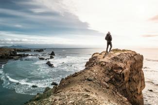 man on edge of cliff by Sead Dedić courtesy of Unsplash.